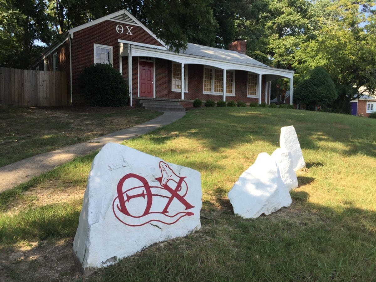 Fraternity house with painted rocks and red door.