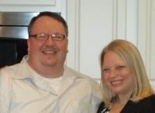 Smiling couple posing in a kitchen setting.