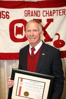 Man holding award in front of banner backdrop.