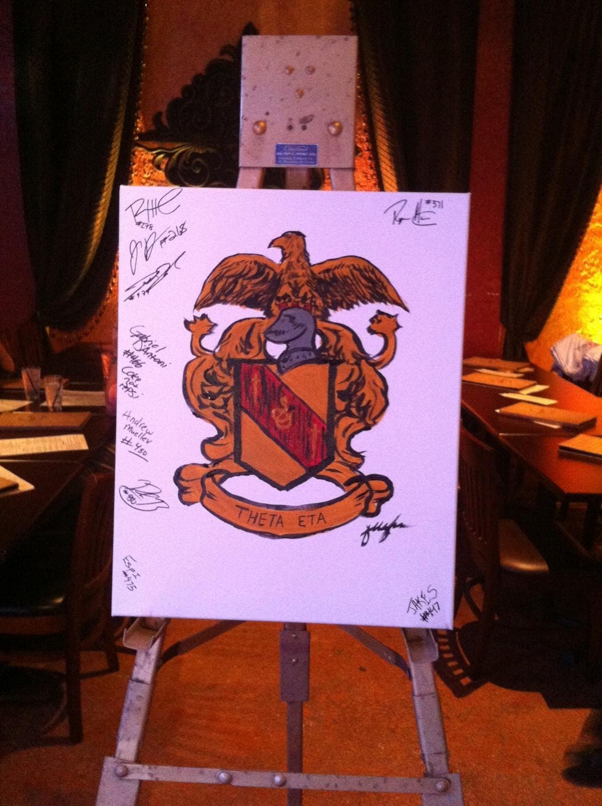 Theta Eta fraternity crest with signatures on canvas.