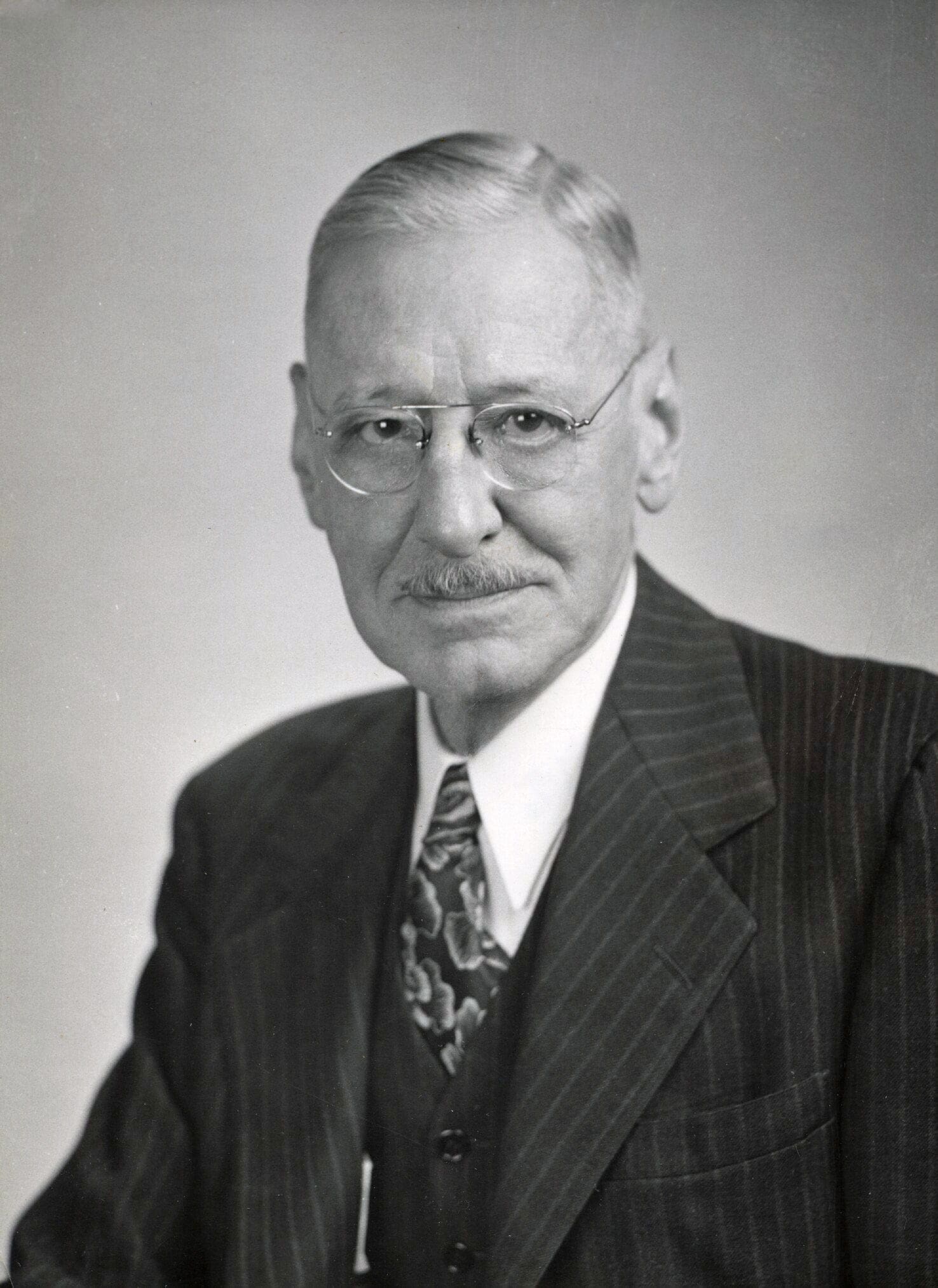 Older man in a suit with glasses, professional portrait.