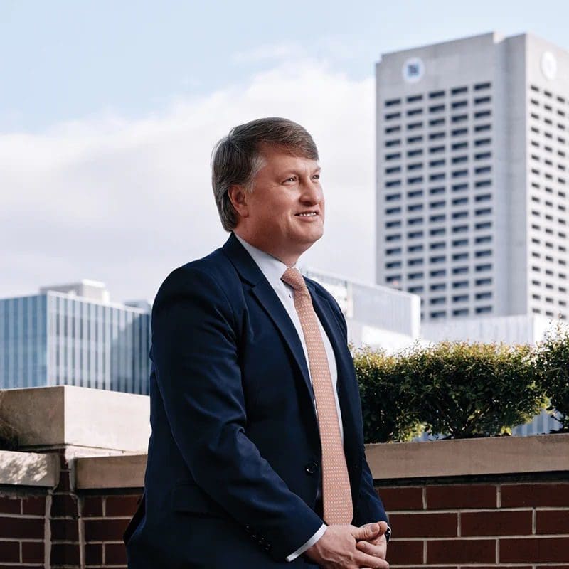 Business professional standing outdoors with city skyline background.