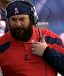 Football coach wearing headset on the sidelines.