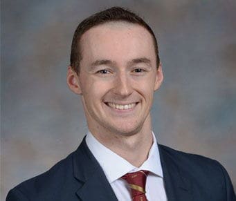 Patrick Zurn Smiling man in a suit against a neutral background.