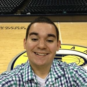 Smiling fan on basketball court with team logo.