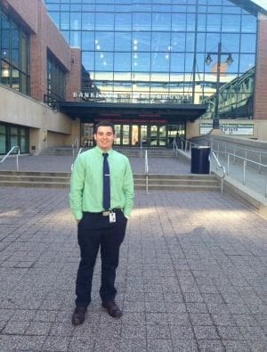 Man in green shirt outside modern building entrance.