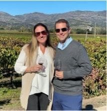Couple enjoying wine tasting in vineyard setting.