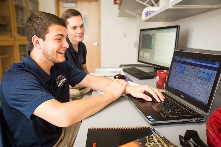 Students collaborating on a laptop in a classroom.