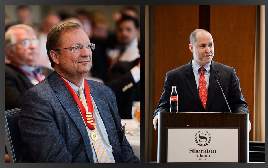 Two men at a formal event, one speaking.