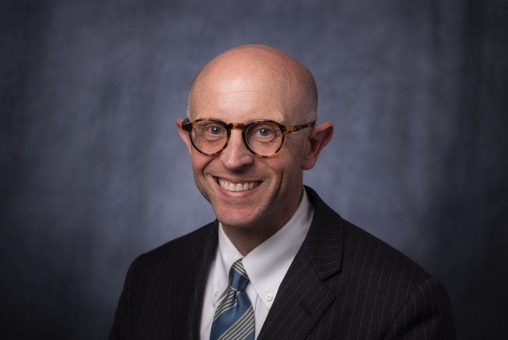 Smiling professional man in suit and glasses.