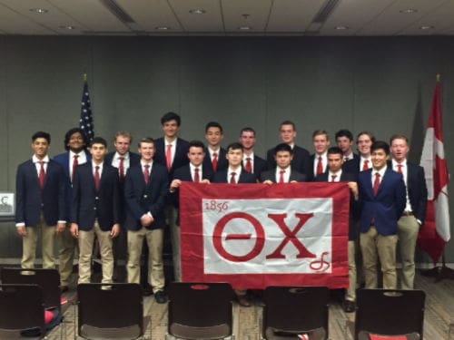 Group of fraternity members holding a flag.