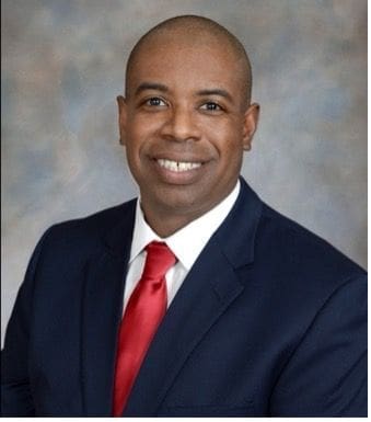 Smiling man in suit with red tie.