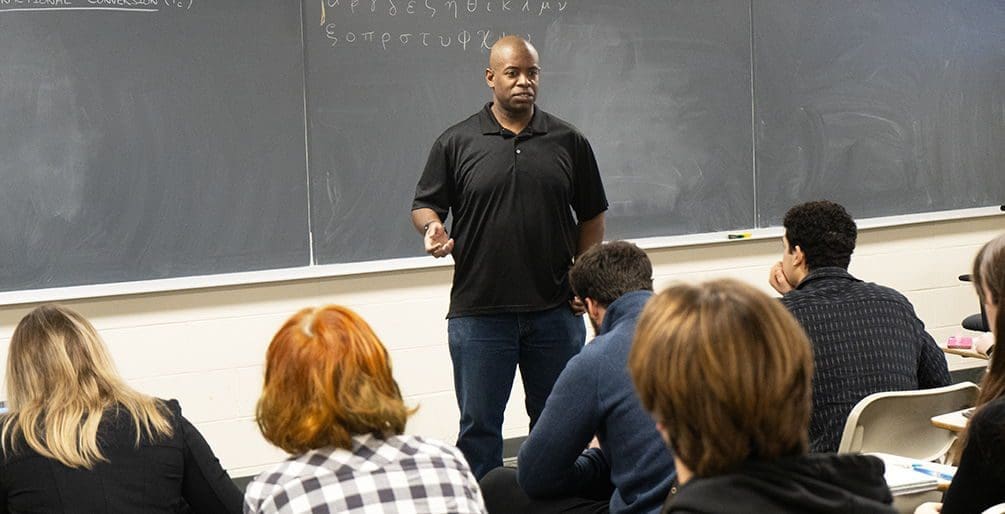 Instructor teaching in front of a classroom setting.