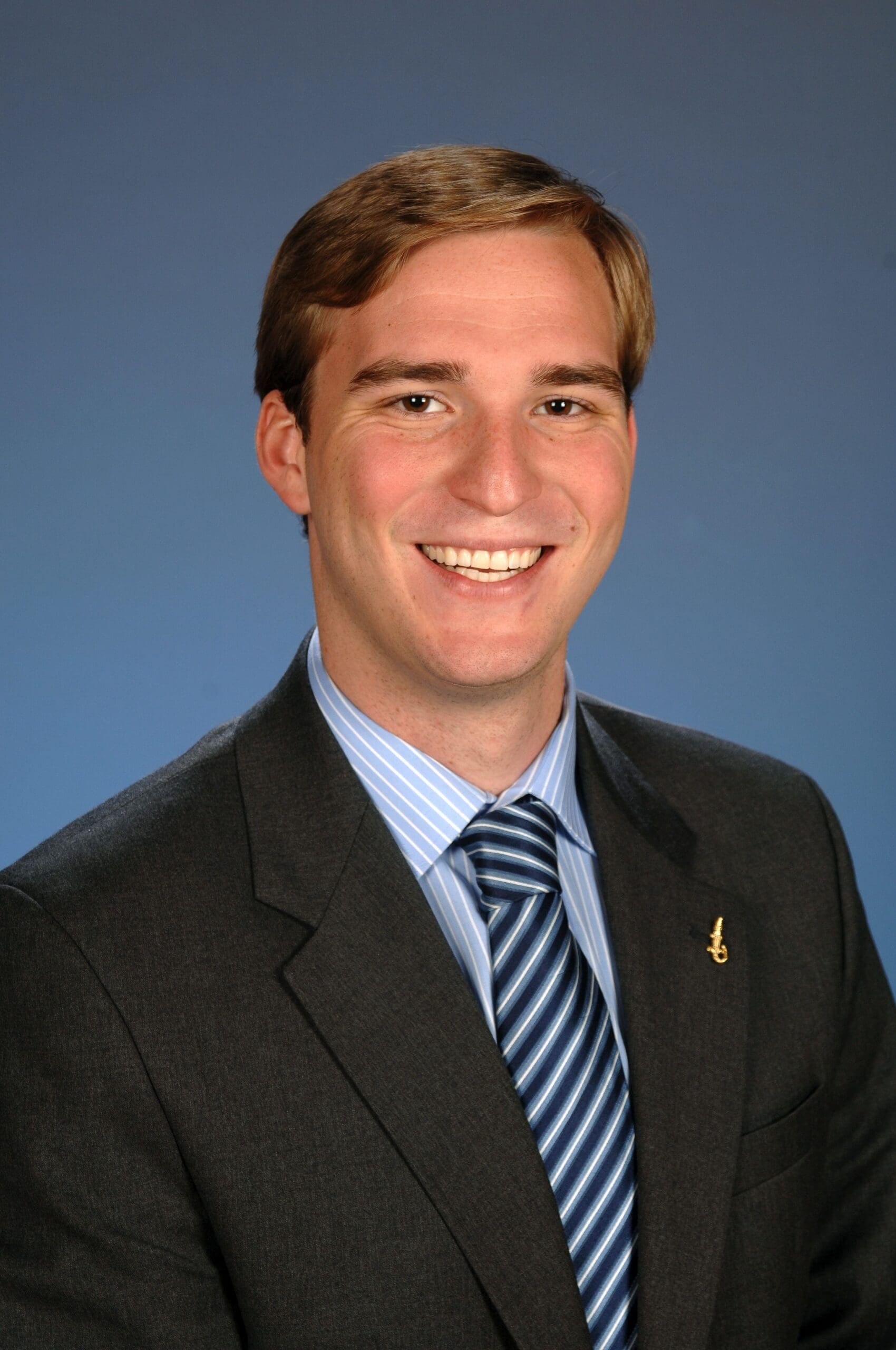 Smiling man in professional suit with blue background.