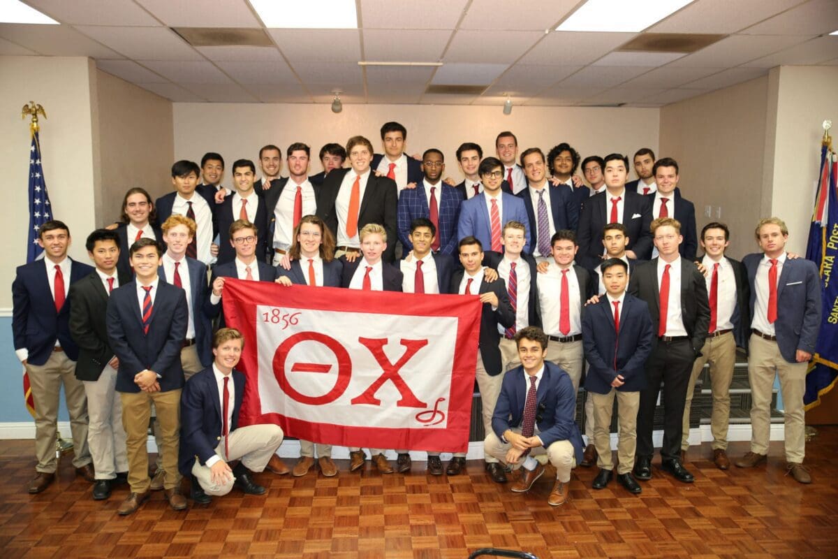 Group photo of fraternity members with banner.