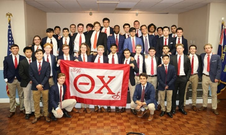 Group of fraternity members holding a flag.