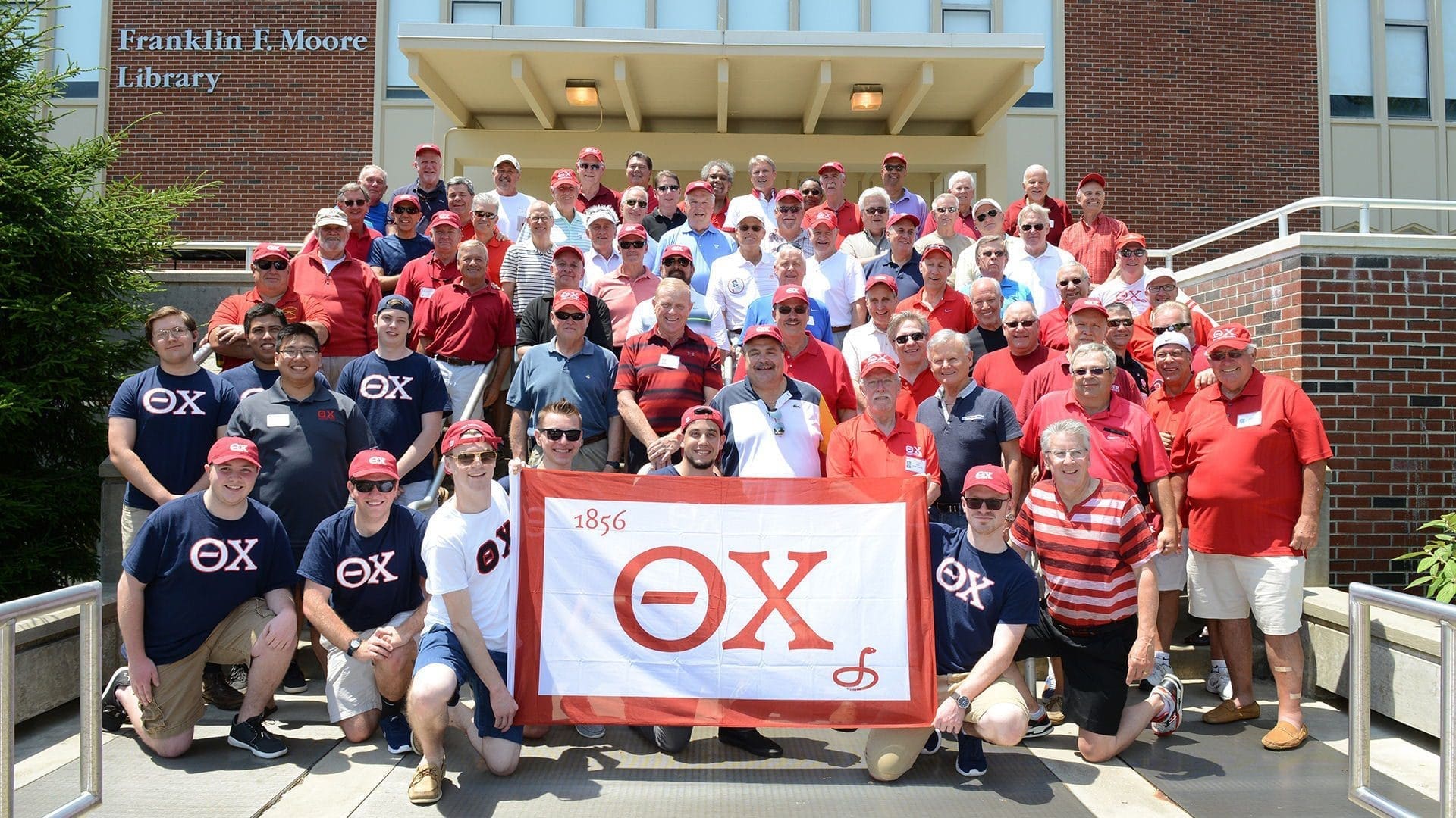 Epsilon Rho - Rider Group photo of alumni holding an Omega Chi banner.