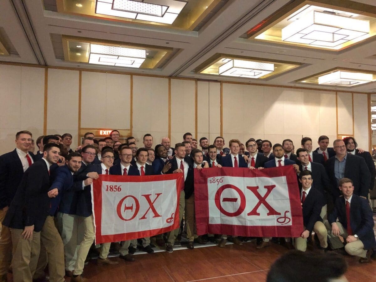 Group of fraternity members holding flags at event.