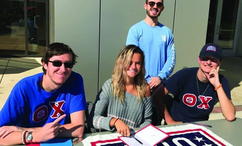 College students at a recruitment table outdoors.