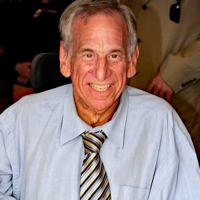 Smiling man in a blue shirt and striped tie.