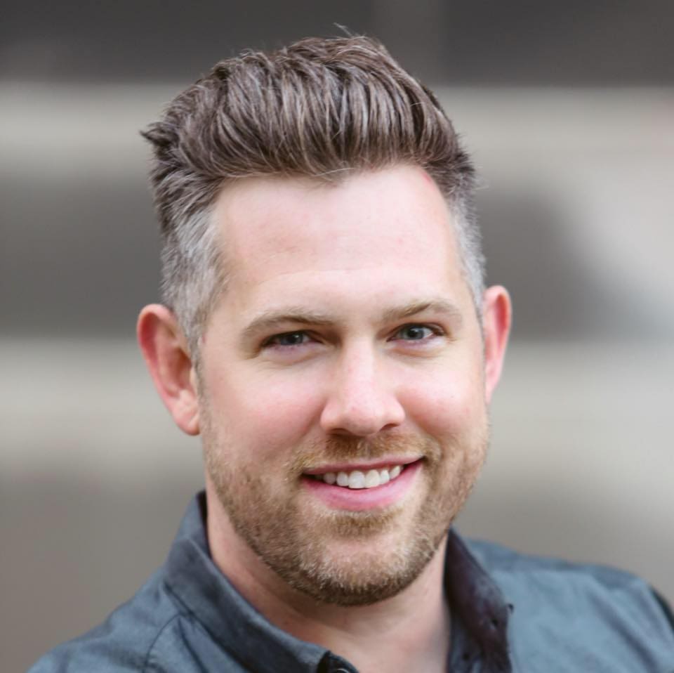 Ryan Ahlwardt Smiling man with stylish hair and casual shirt.