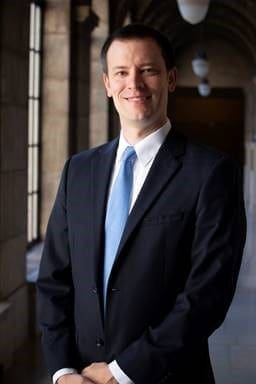 Gamma Phi - Nebraska Wesleyan - Ryan Post Professional man in business suit smiling indoors.