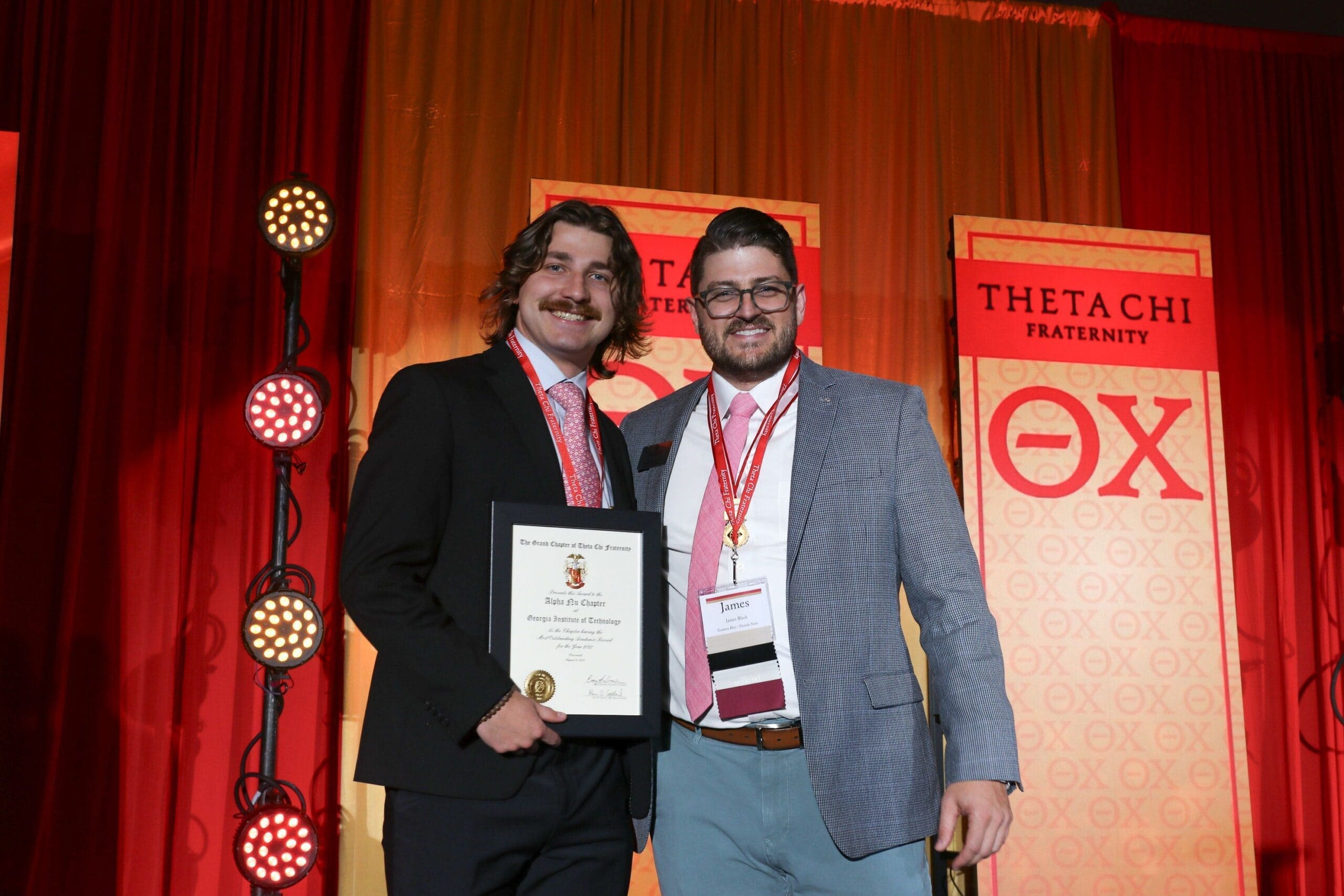 Two men celebrating an award at Theta Tau event.