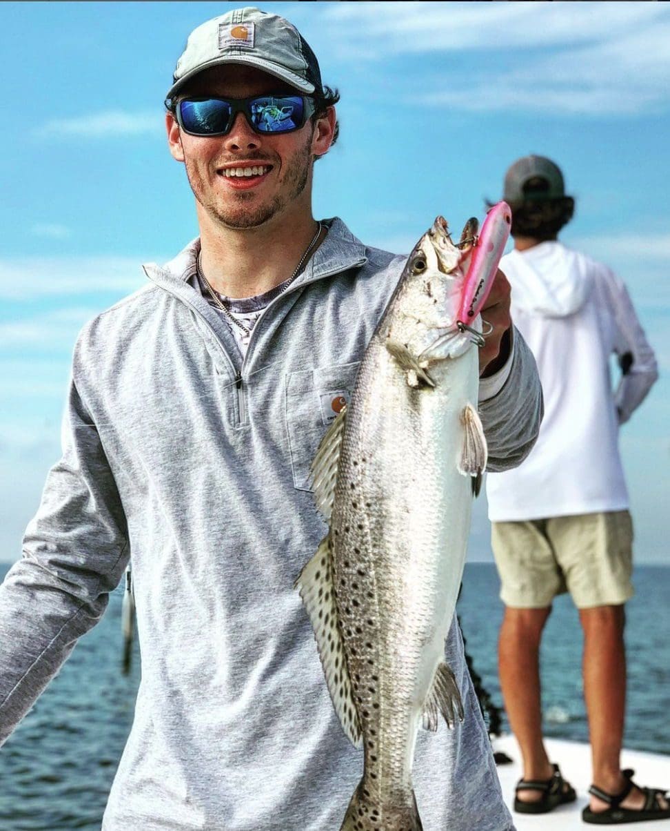 Young man holding a large fish on a boat.
