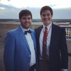 Two men in formal attire smiling outdoors.