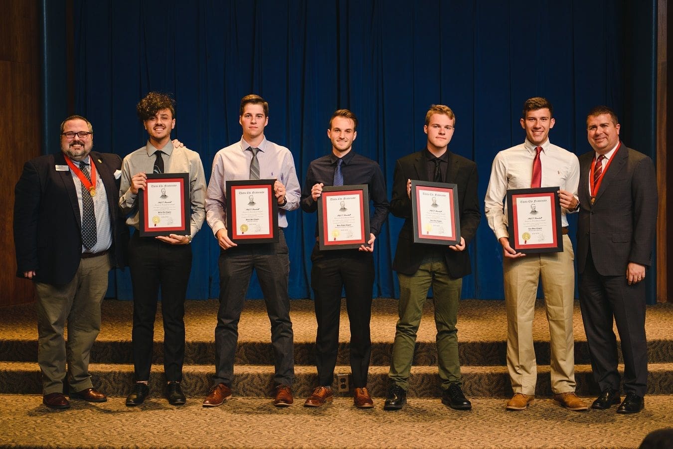 Students holding awards at a recognition ceremony.