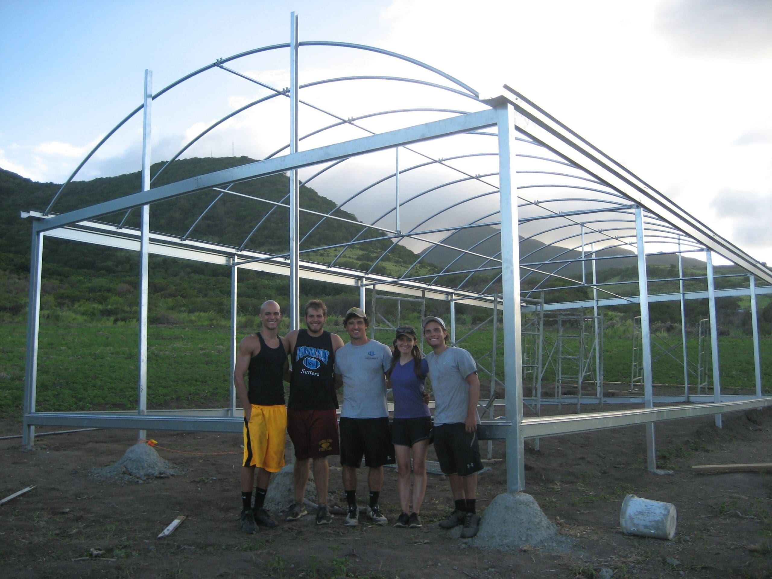 Group of people near greenhouse construction site.