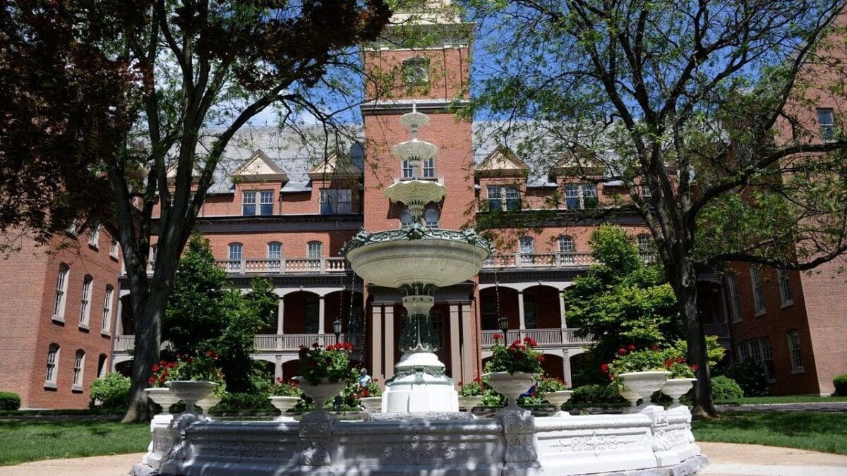 Historic building with fountain and lush greenery.