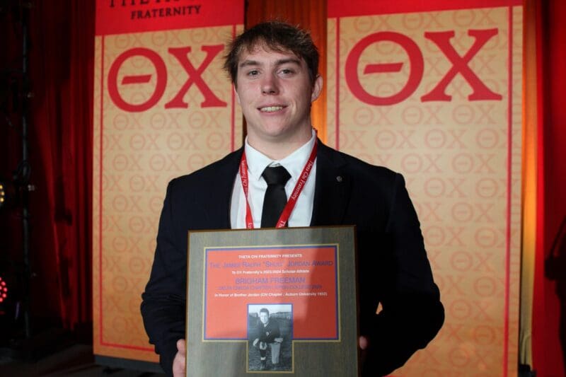 Young man holding award at fraternity event.