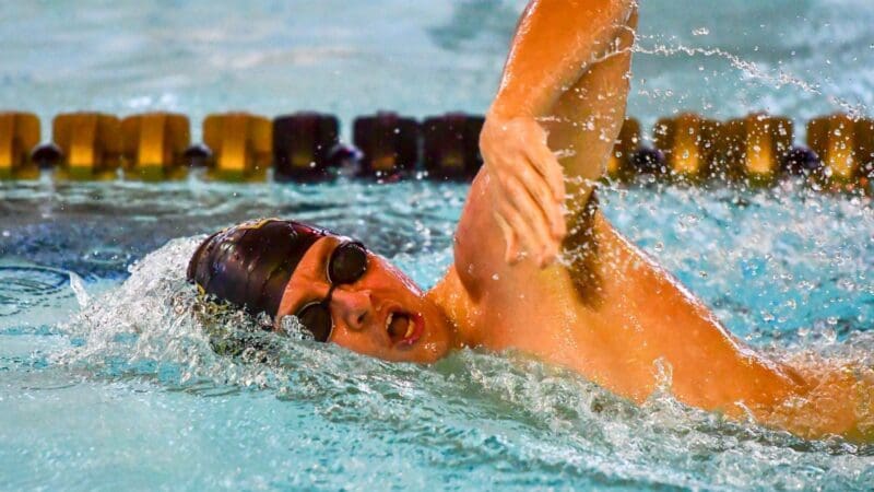 Swimmer performing freestyle stroke in pool.