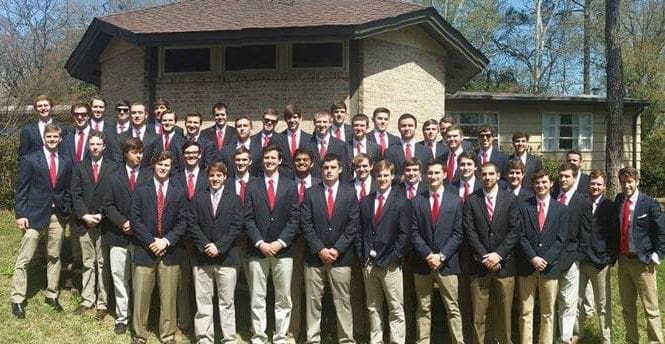 Group of male students in formal attire outside building.