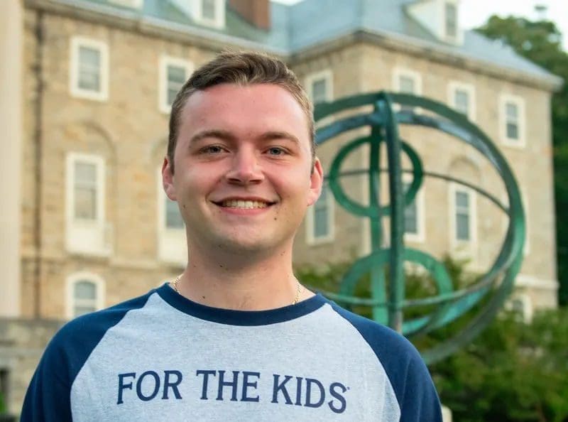 Smiling young man in "For the Kids" shirt.