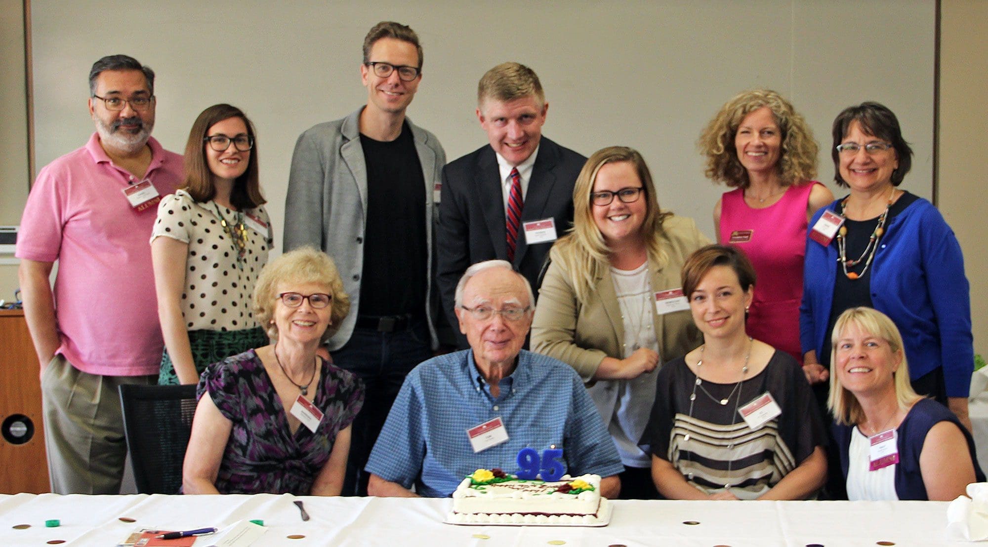 Group celebrating 96th birthday with cake and smiles.