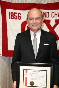 Man holding award in front of a banner.