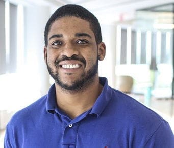 Smiling man in blue polo shirt indoors.