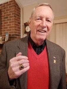 Elderly man in blazer holding a ring.