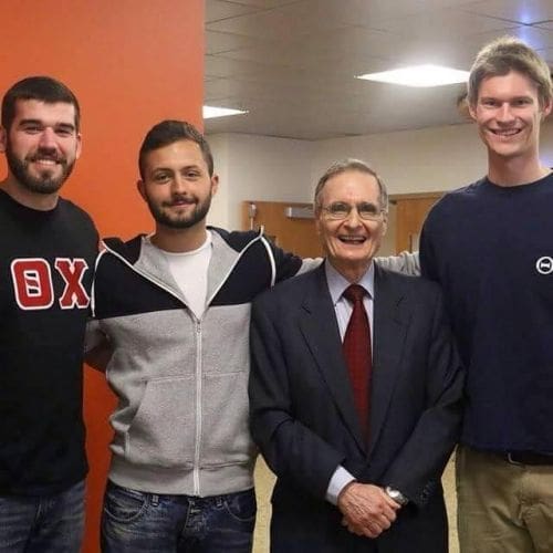 Group of four men posing together in a hallway.