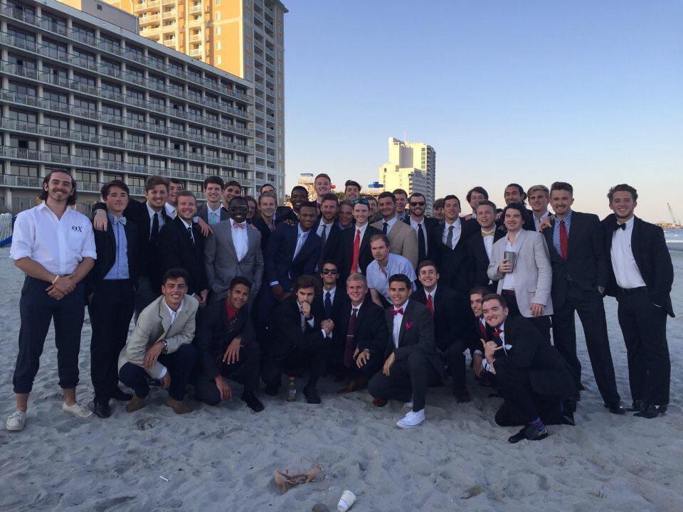 Group of men in suits at the beach.