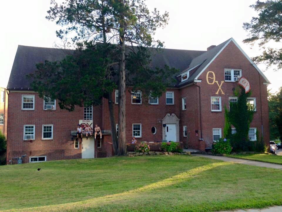 Brick building with Greek letters and landscaped yard.