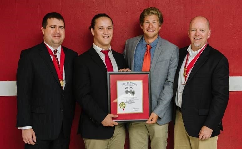 Four men holding an award certificate together.