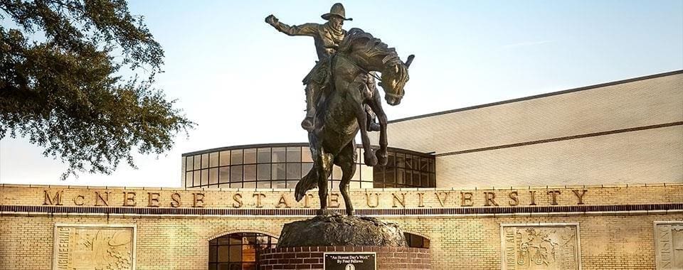 Statue of cowboy on horse at university campus.