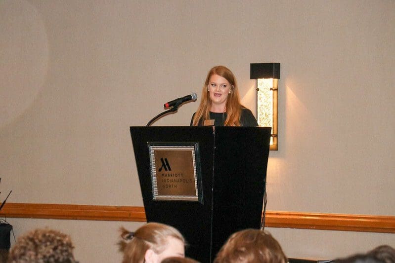 Woman speaking at conference podium in hotel.