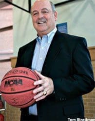 Man in suit holding basketball indoors.