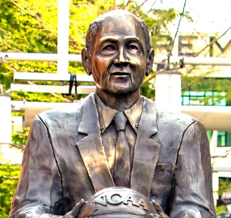 Bronze statue of a basketball coach holding a ball.