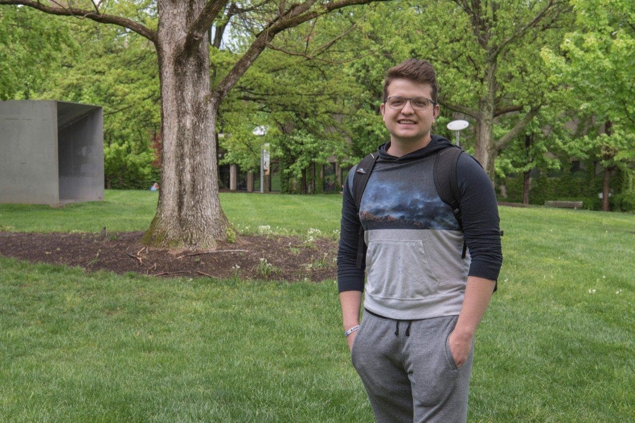 Smiling young man standing in green park.