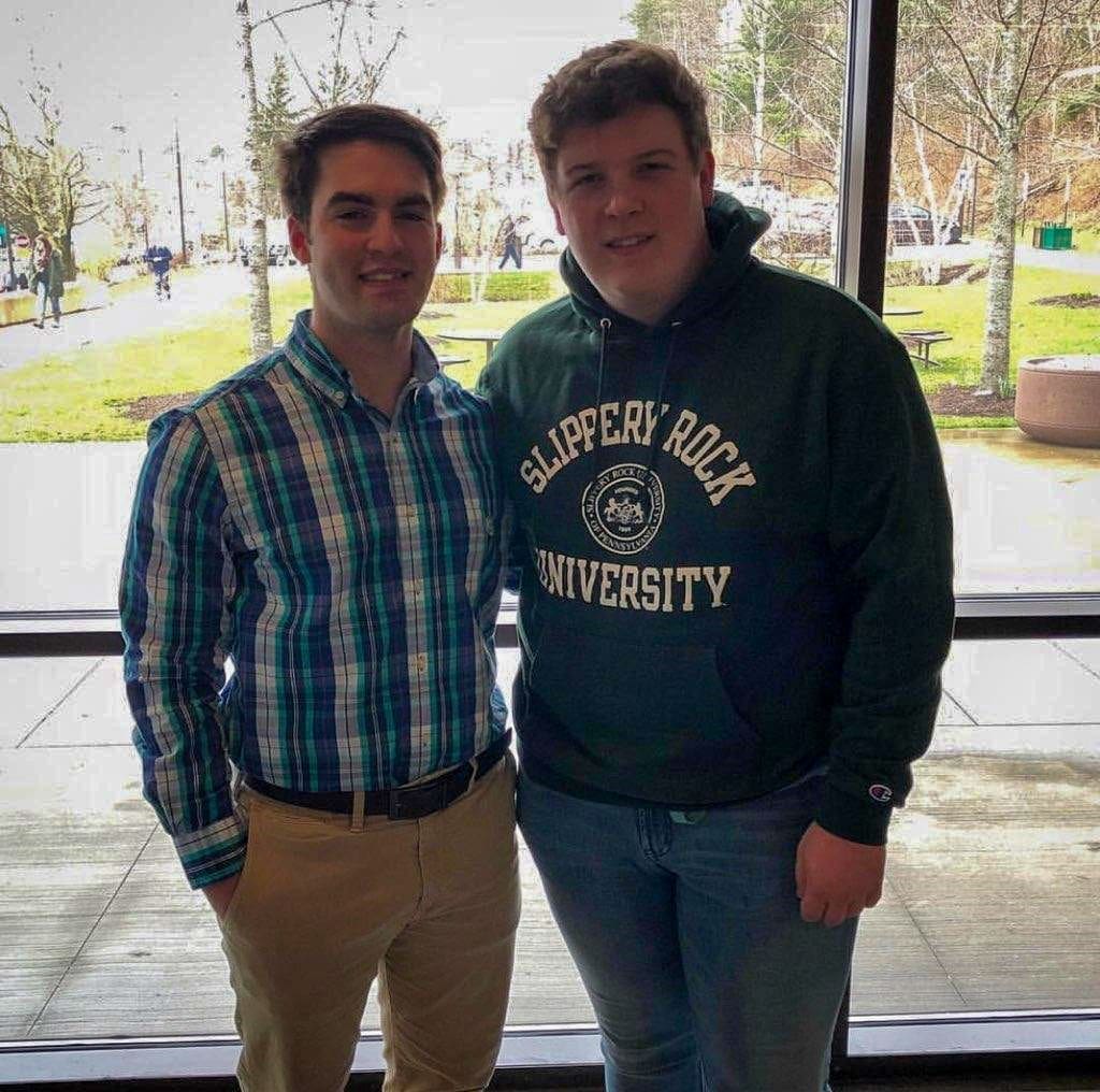 Two young men posing indoors, smiling together.
